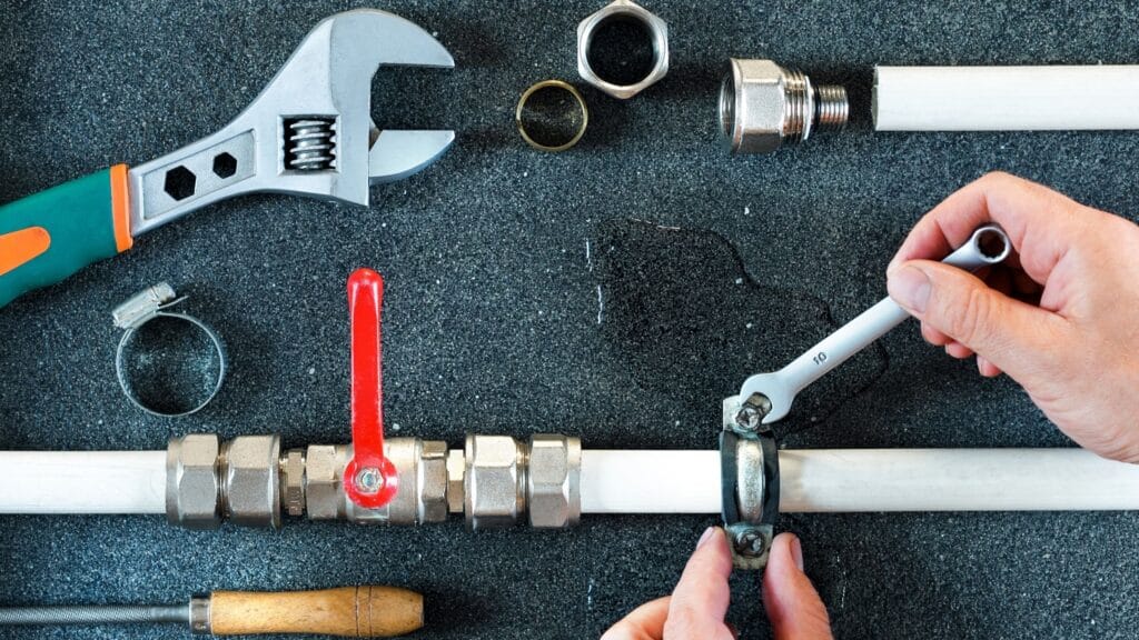 Plumber repairing a pipe valve with an adjustable wrench in Bloomington