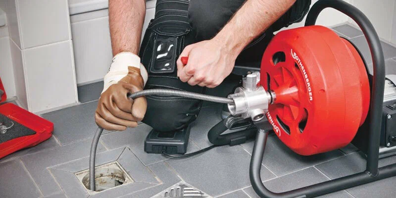 Plumber using a drain-cleaning machine in Bloomington
