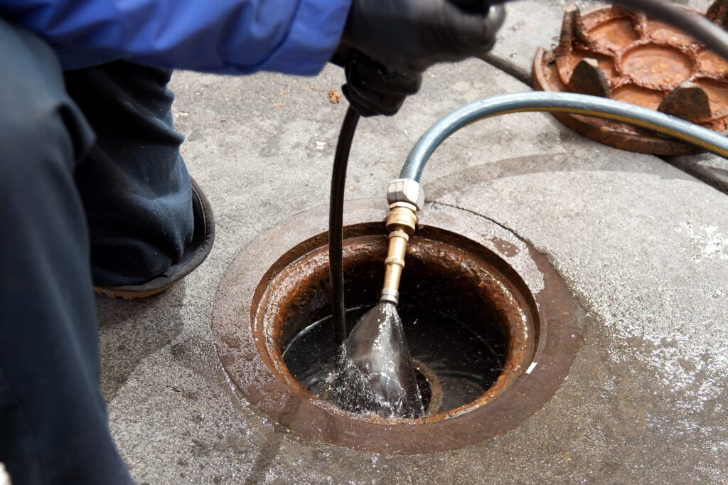 Plumber hydro jetting a sewer line through a manhole in Bloomington