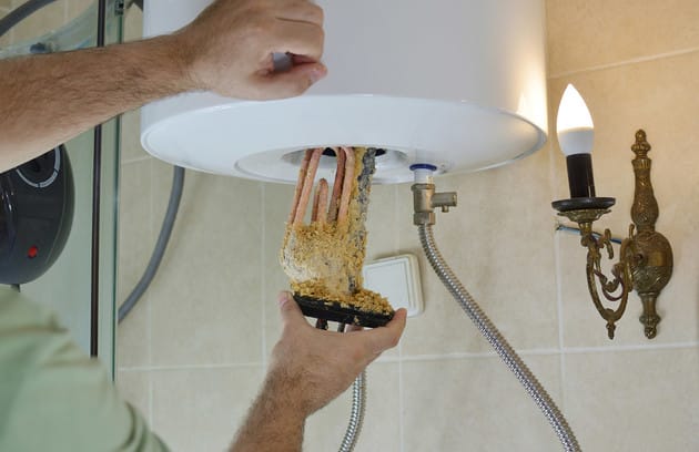 Technician removing mineral buildup from a water heater in Bloomington