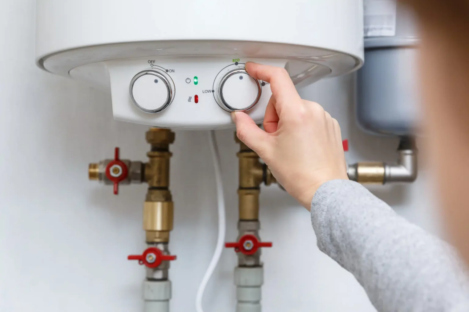Homeowner adjusting the temperature controls on a water heater in Bloomington